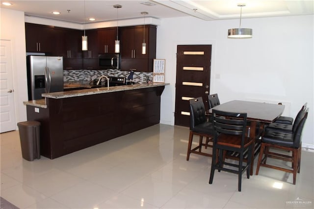 kitchen with appliances with stainless steel finishes, tasteful backsplash, light stone countertops, dark brown cabinets, and recessed lighting