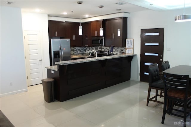 kitchen featuring a peninsula, tasteful backsplash, dark brown cabinets, and stainless steel appliances