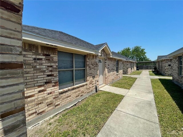2015 W Western St, Edinburg, TX 78539 - view of side of property with brick siding, roof with shingles, and a yard