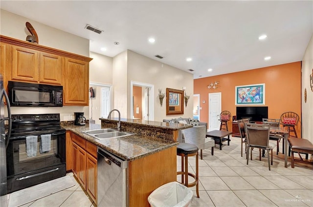 103 Gardenia St Unit 3, South Padre Island, TX 78597 - kitchen featuring black appliances, a sink, a peninsula, a kitchen breakfast bar, and light tile patterned floors