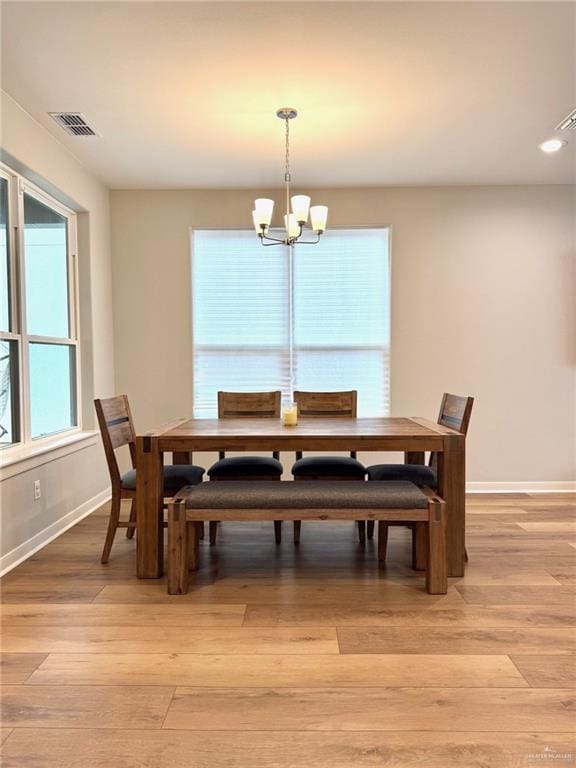 dining room with light hardwood / wood-style floors and a notable chandelier