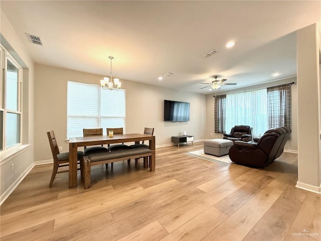 dining area with ceiling fan with notable chandelier, light hardwood / wood-style flooring, and a healthy amount of sunlight