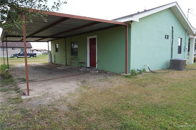 exterior space featuring a yard, a carport, and cooling unit