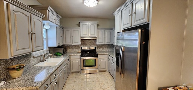 kitchen featuring decorative backsplash, sink, light stone countertops, and stainless steel appliances