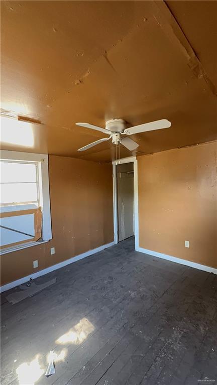 spare room with a ceiling fan and baseboards