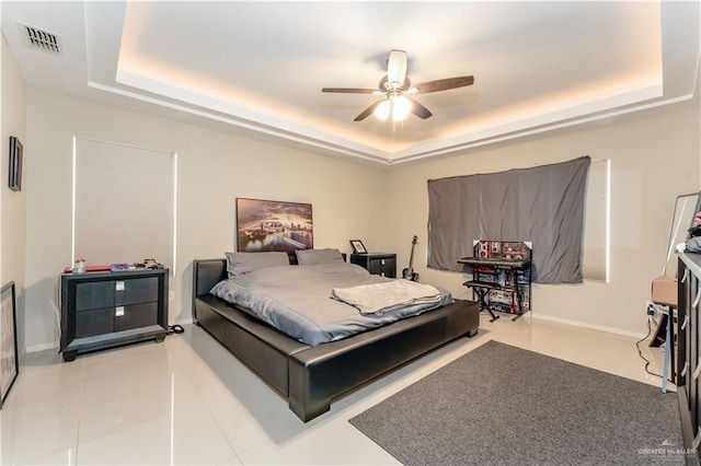 bedroom with visible vents, a tray ceiling, and baseboards