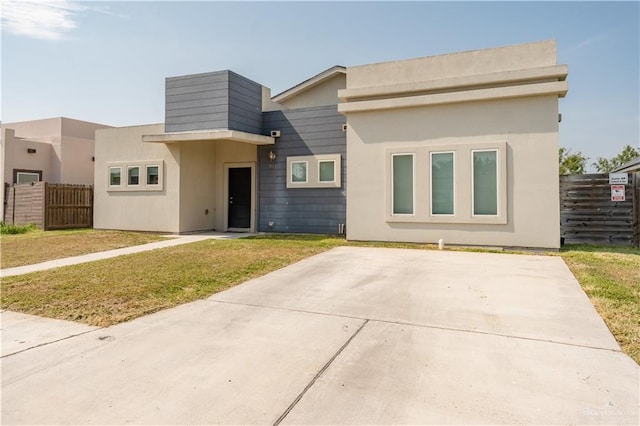 view of front of property featuring stucco siding, fence, and a front yard