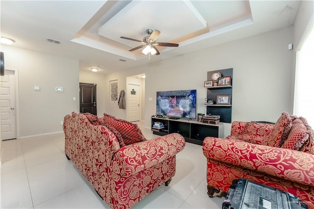 living area with a raised ceiling, visible vents, ceiling fan, and light tile patterned flooring