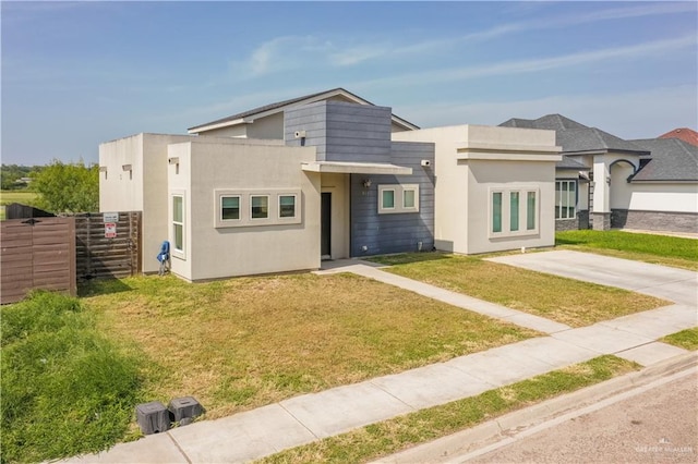 view of front facade featuring fence, a front lawn, and stucco siding