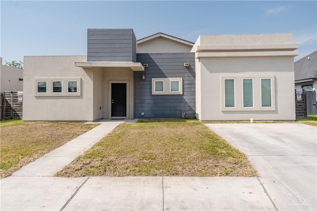 view of front facade with a front lawn, fence, and stucco siding