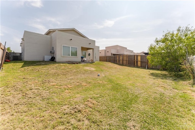 rear view of house featuring a fenced backyard and a yard