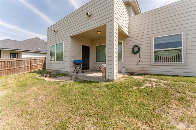 rear view of house with a yard, a patio, and fence