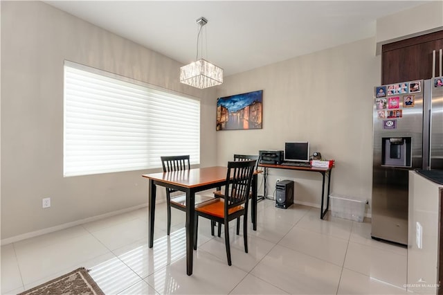 dining space with light tile patterned floors, baseboards, and a notable chandelier