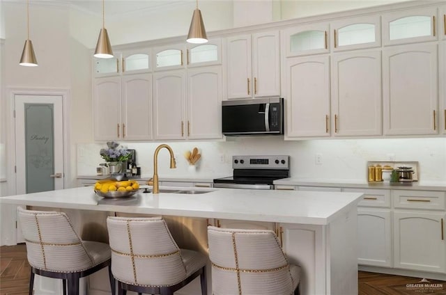 kitchen featuring dark parquet floors, an island with sink, white cabinetry, sink, and stainless steel appliances