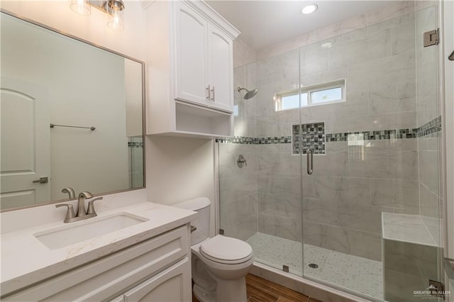 bathroom featuring hardwood / wood-style flooring, vanity, toilet, and a shower with door