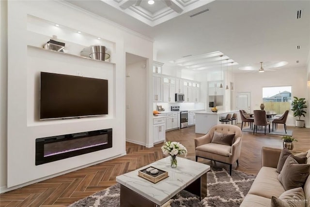 living room with dark parquet flooring, ornamental molding, and ceiling fan