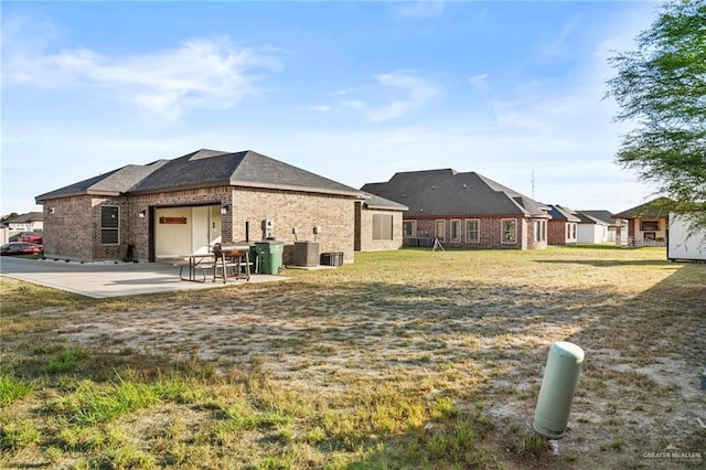 rear view of house with a lawn, central AC, and a patio area