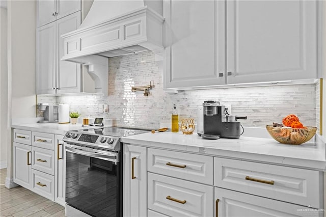 kitchen featuring white cabinetry, tasteful backsplash, light hardwood / wood-style floors, electric stove, and custom range hood