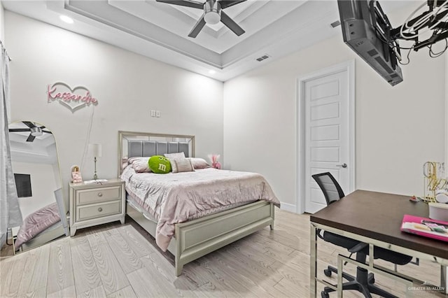 bedroom featuring a raised ceiling, ceiling fan, and light wood-type flooring