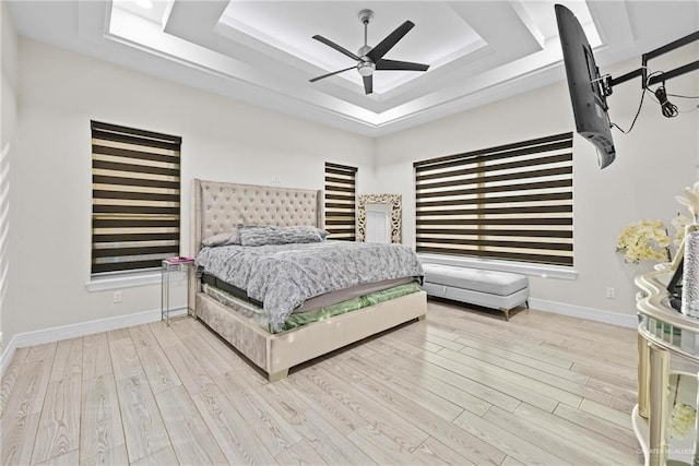 bedroom with a tray ceiling, light hardwood / wood-style flooring, and ceiling fan