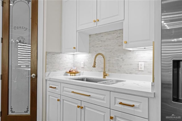 kitchen featuring light stone counters, white cabinetry, tasteful backsplash, and sink