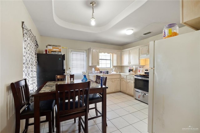 kitchen with a tray ceiling, stainless steel electric range oven, light tile patterned floors, and white refrigerator