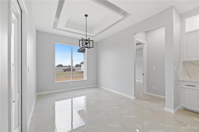 unfurnished dining area featuring a raised ceiling