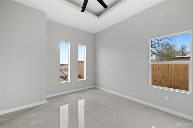 spare room with ceiling fan and a tray ceiling