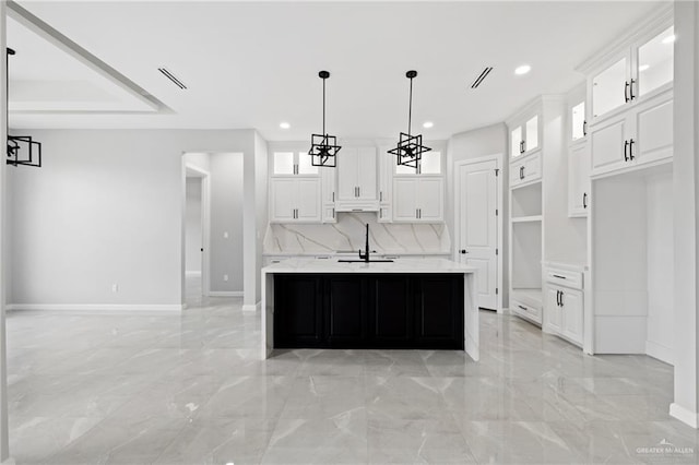 kitchen with a center island with sink, hanging light fixtures, sink, white cabinets, and decorative backsplash