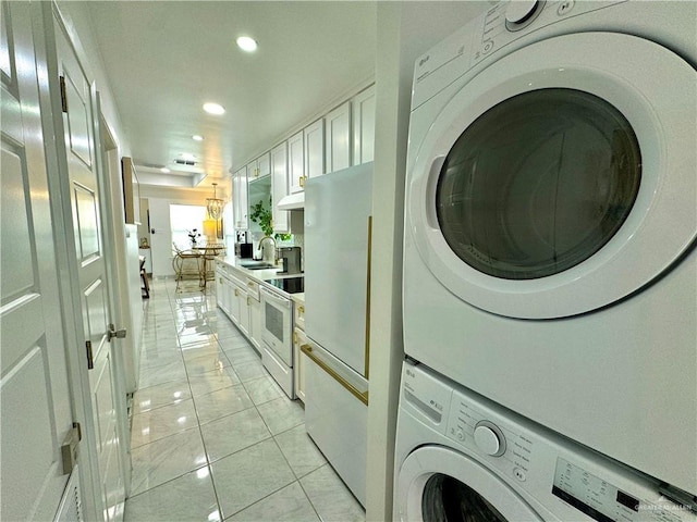 laundry area with light tile patterned flooring, sink, and stacked washer / dryer