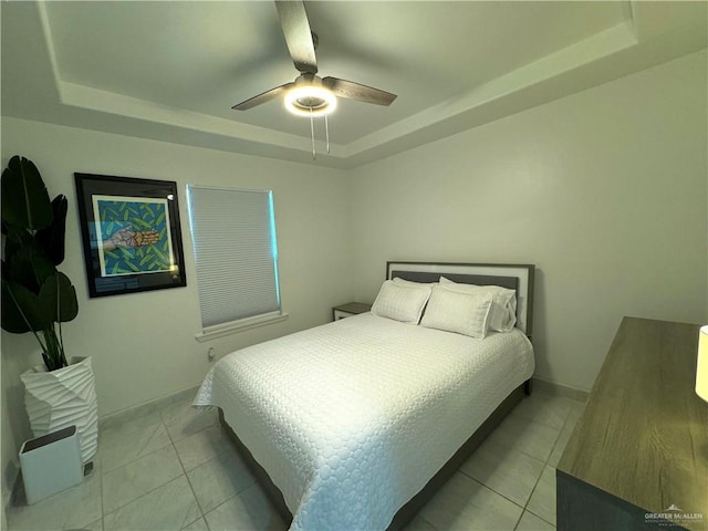 bedroom featuring light tile patterned floors, a raised ceiling, and ceiling fan