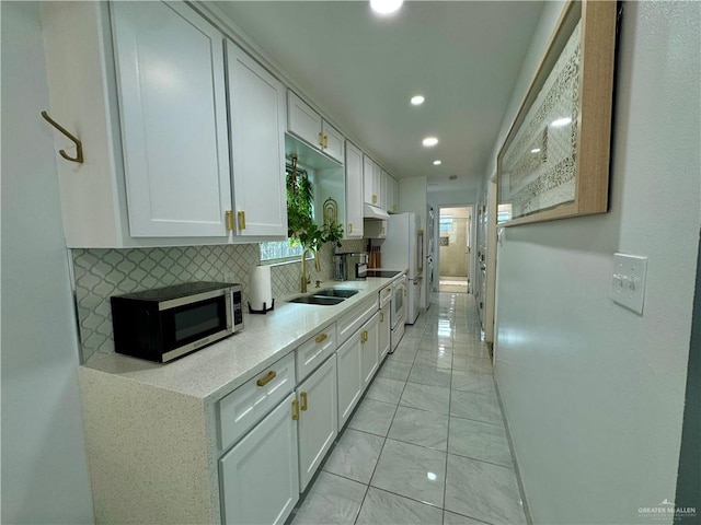 kitchen with white appliances, white cabinetry, sink, and tasteful backsplash