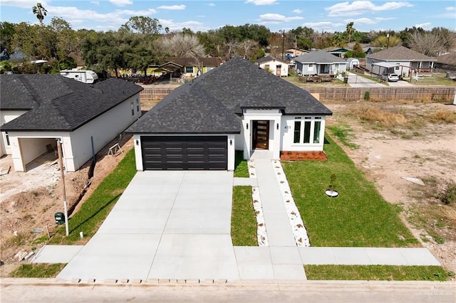 view of front facade featuring a garage, driveway, roof with shingles, a residential view, and a front yard