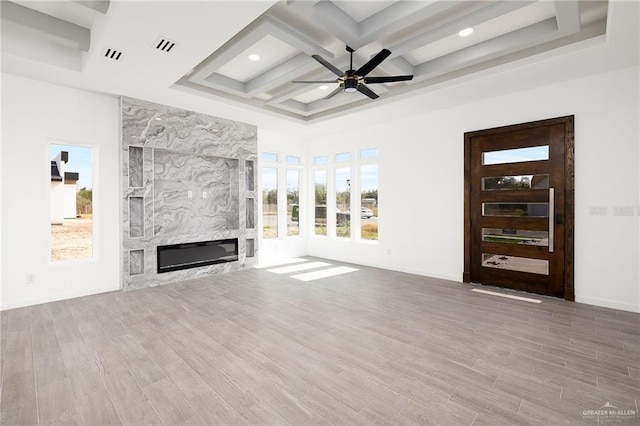 unfurnished living room with coffered ceiling, ceiling fan, wood finished floors, a fireplace, and beam ceiling