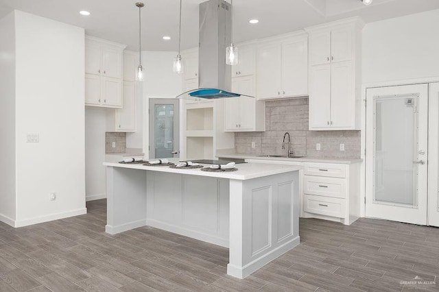 kitchen with wood finished floors, a sink, white cabinetry, and island range hood