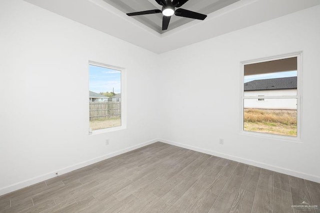 unfurnished room featuring wood finished floors, a raised ceiling, and baseboards