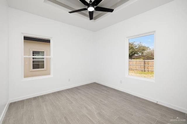 unfurnished room with a tray ceiling, ceiling fan, baseboards, and wood finished floors