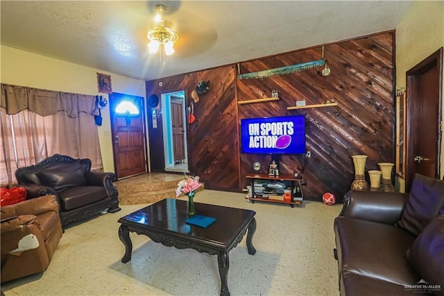 living room with a textured ceiling and wood walls