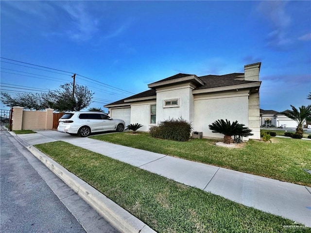 view of property exterior featuring concrete driveway, an attached garage, fence, a yard, and stucco siding