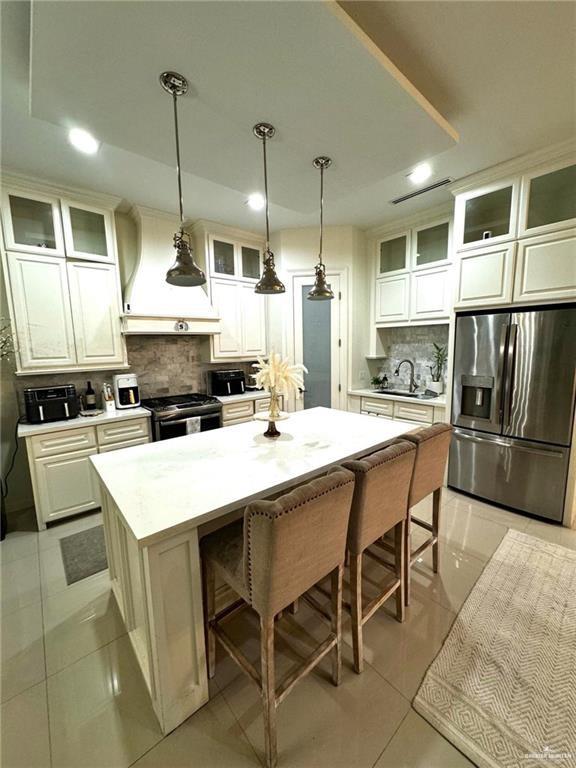 kitchen with a center island, stainless steel appliances, decorative backsplash, glass insert cabinets, and a sink