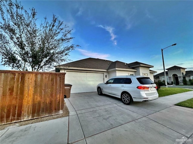 view of front of property featuring concrete driveway, an attached garage, and fence