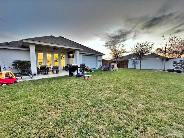 rear view of property featuring a ceiling fan, a fenced backyard, a yard, a patio area, and stucco siding