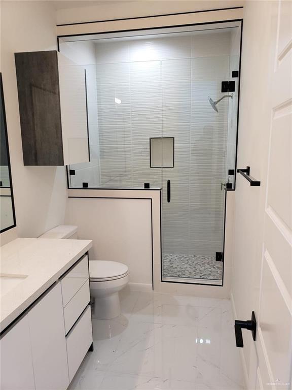 bathroom featuring vanity, a shower stall, toilet, and marble finish floor