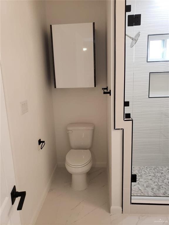 bathroom with a shower stall, toilet, baseboards, and marble finish floor