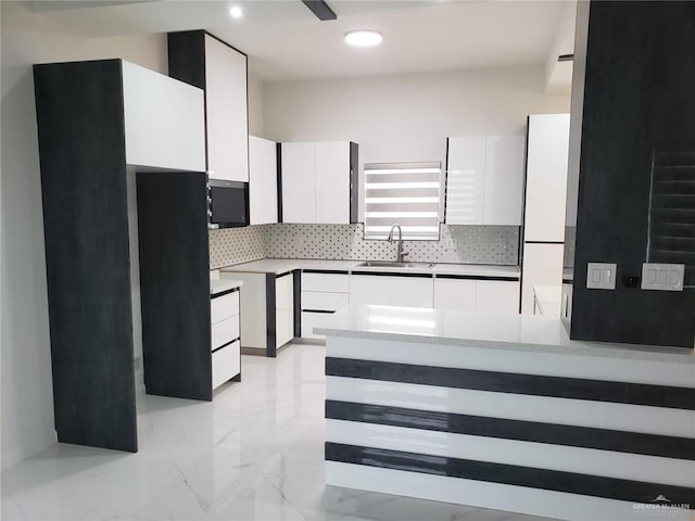 kitchen featuring white cabinets, modern cabinets, backsplash, and a sink