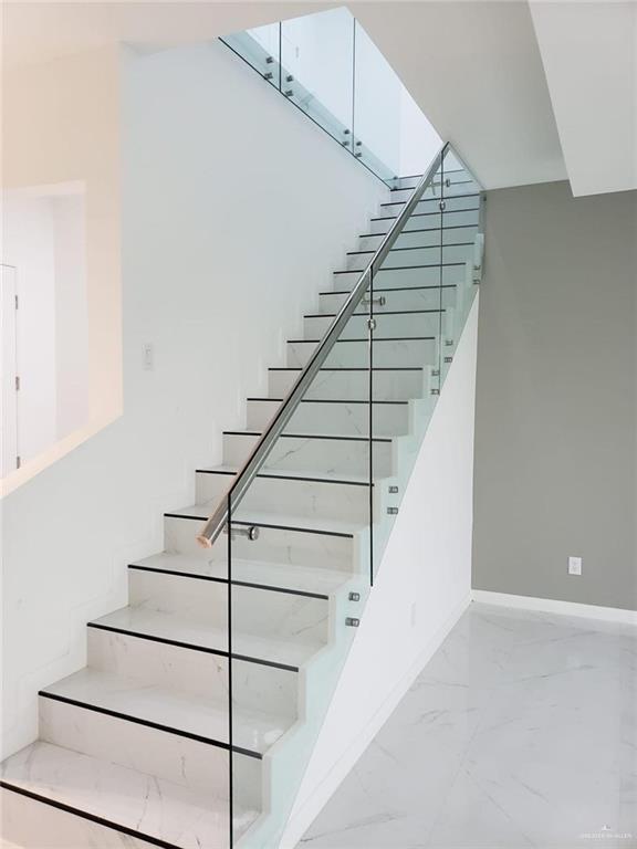 staircase featuring baseboards and marble finish floor