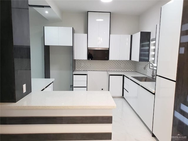 kitchen featuring a sink, decorative backsplash, white cabinets, modern cabinets, and marble finish floor