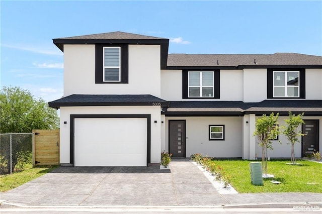 view of front of house with stucco siding, driveway, fence, a front yard, and a garage