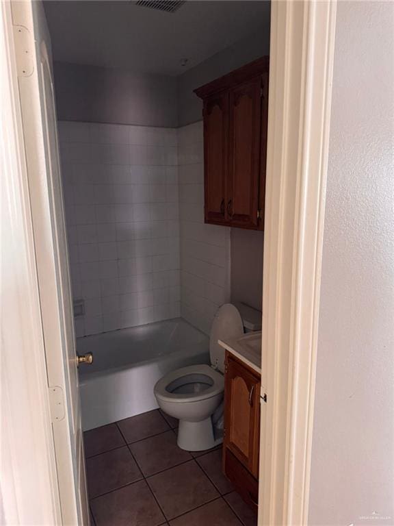 full bathroom featuring vanity, tiled shower / bath, tile patterned floors, and toilet