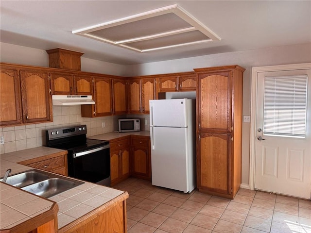 kitchen featuring range with electric cooktop, tile countertops, sink, backsplash, and white refrigerator